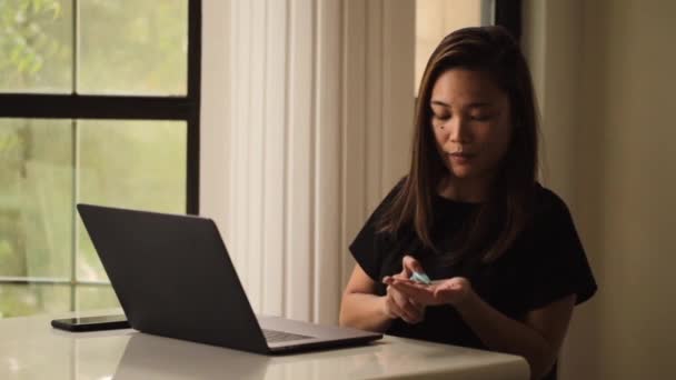 아시아 여성 이 집에서 노트북으로 인터넷 검색을 하고 있습니다. 코로나 바이러스에 대한 사회적 확장 예방. 보호를 위해 손으로 소독하는 일. — 비디오