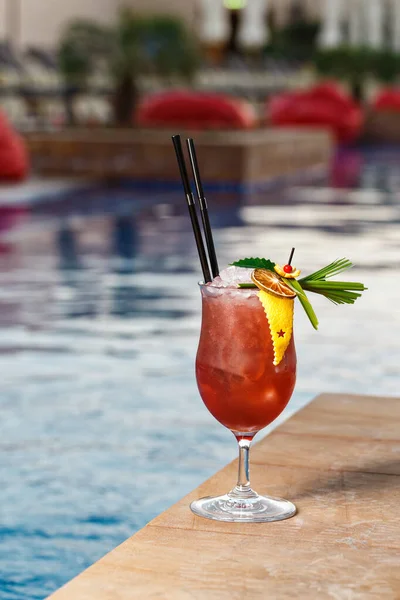 Refreshing mocktail with ice cubes perfect for outdoor event. Fancy beverage decoration with crafted leaf, lemon sliced and orange zest. Pool side area in hotel.