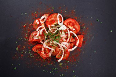 Dilimlenmiş domates, yeşillikli soğan ve biber tozu. Siyah arka plan. Orta Asya mutfağı