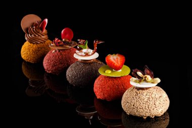 Choux kremi. Kremalı ve çilekli ahududu soslu. Siyah arkaplan portresindeki şekerleme fotoğrafçılığı konsepti. Sanat tatlısı