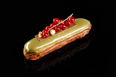 Kremalı ekler ve şam fıstığı jölesiyle kaplanmış zarif dekoratif yaban mersini. Siyah arkaplanda şekerleme fotoğrafçılığı kavramı.