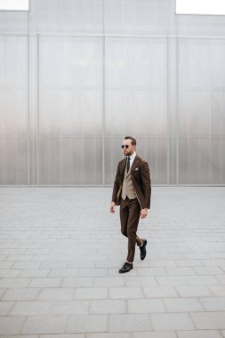 Kahverengi takım elbiseli ve kravatlı bir iş adamı gündüz gözlüğü takıyor. Erkek işi dergi kapağı ya da giysi resimleri için model fotoşoplar giyer.