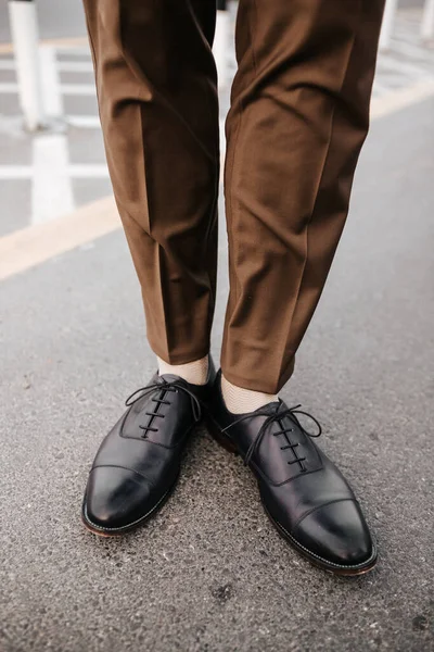 Mans feet image with brown trouser and black leather shoes for fashion magazine outdoor photography concept