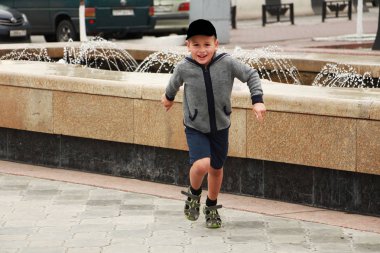 Küçük bir çocuk çeşmenin yanında koşuyor.