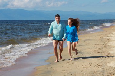 Adam ve kız sahilde koşuyorlar.