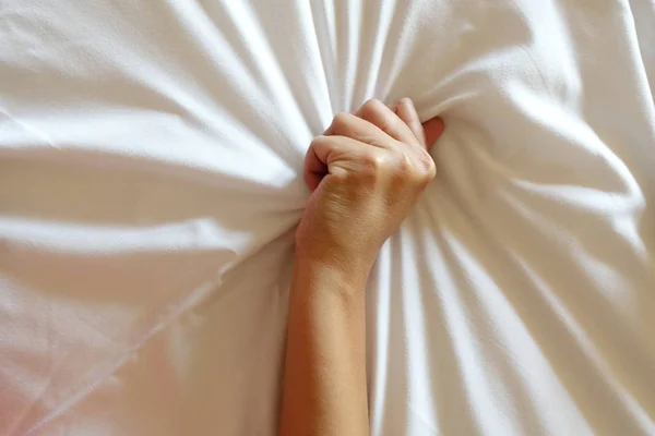 Main de femmes tirant des draps blancs en extase, orgasme . Image En Vente