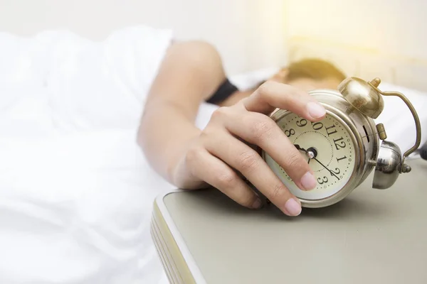 Giovane donna con sveglia sul letto al mattino — Foto Stock