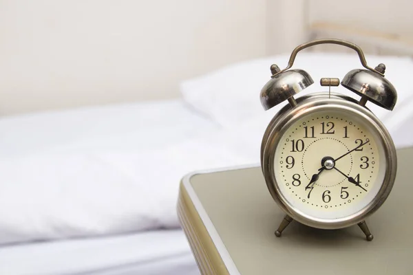 Ung kvinna med väckarklocka på sängen på morgonen — Stockfoto