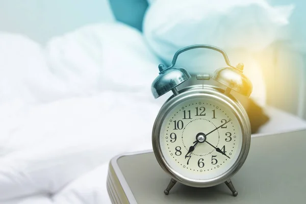 Young woman with alarmclock on the bed at the morning — Stock Photo, Image