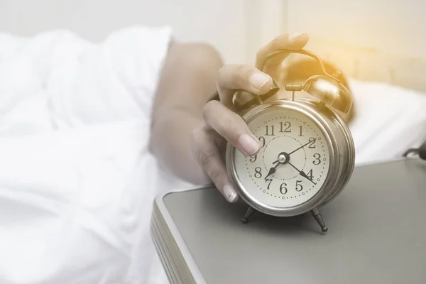 Jeune femme avec réveil sur le lit le matin — Photo