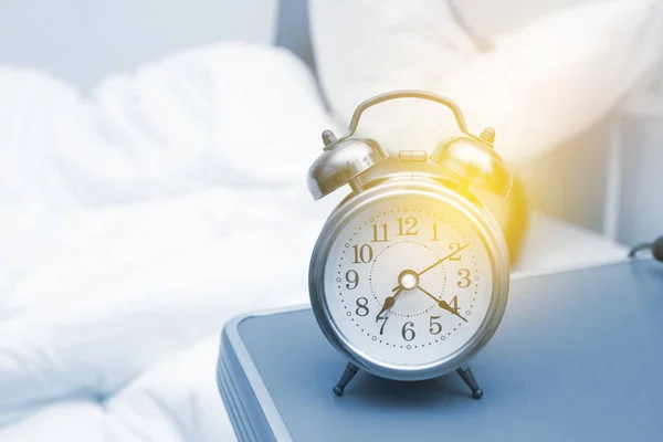 Jeune femme avec réveil sur le lit le matin — Photo