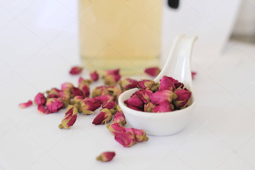 Rose buds tea, tea cup, strainer and glass jar with rosebuds.