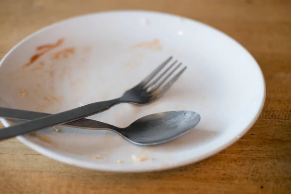 Piatto sporco con cucchiaio e forchetta dopo un pasto — Foto Stock