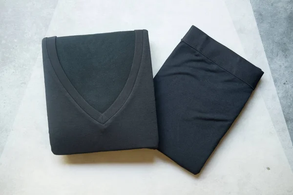 Pants and t-shirt black folded for winter season. Technology from japan that call Heattech can help to generate heat and keep body warm