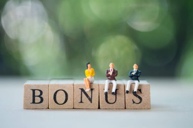 Minyatür insanlar: Bonus 'un ahşap bloğunda oturan personel ikramiye bekliyor. İkramiye ödülü kâr teşviki ek tazminat kavramı