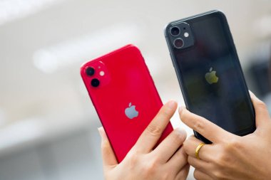 Bangkok, Tayland - 24 Kasım 2019: 11 kırmızı ve siyah iPhone 'un iki kadın el ele tutuşması. Apple şirketinden akıllı telefonlar..