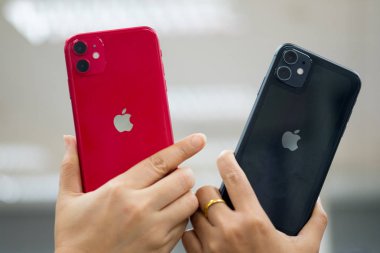 Bangkok, Tayland - 24 Kasım 2019: 11 kırmızı ve siyah iPhone 'un iki kadın el ele tutuşması. Apple şirketinden akıllı telefonlar..