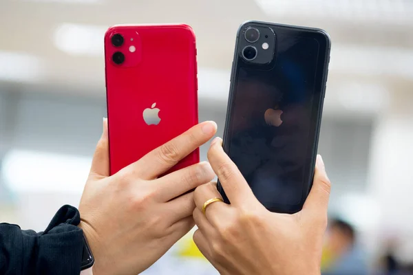 Бангкок, Таиланд - 24 ноября 2019 года: две женщины держат в руках новый продукт iPhone 11 красного и черного цвета. Смартфоны от Apple . — стоковое фото