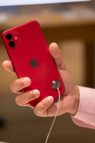 Бангкок, Таиланд - 24 ноября 2019 года: мужчина держит в руке новый красный iPhone 11 в Apple Store на заднем плане — стоковое фото