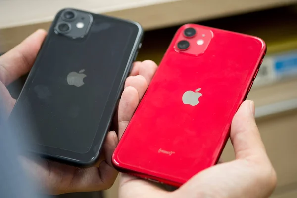 Бангкок, Таиланд - 25 ноября 2019 года: мужчина держит в руке iPhone 11 два мобильных телефона с красным и черным цветами. iPhone 11 был создан и разработан Apple inc . — стоковое фото