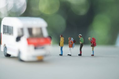 Seyahat ve ulaşım kavramı. Gezgin minyatür figürlü ve küçük oyuncak minibüs modelli sırt çantalı grubu kapatın..