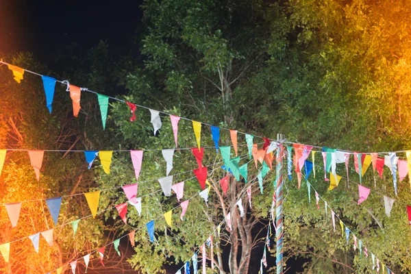 Many multicolored triangle flags hanging on a wire in the night