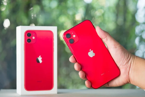 Бангкок, Таиланд - 24 ноября 2019 года: Apple iPhone 11 PRODUCT REDUCT в руке на фоне природы. Крупный план нового смартфона от Apple и коробки — стоковое фото