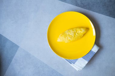 Sarı tabakta basit, yumuşak bir omlet.