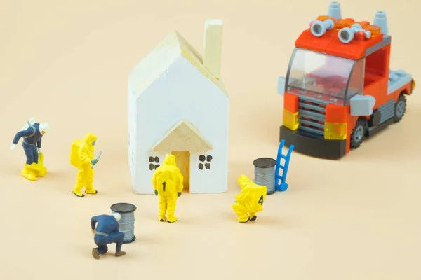 Мініатюрні люди фігури пожежників в небезпечних костюмах, які досліджують навколо будинку — стокове фото