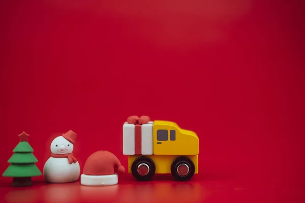 Speelgoed van kerstboom, geschenkdoos op vrachtwagen, sneeuwpop en kerstman hoed op rode achtergrond met kopieerruimte. Begin van het seizoen. Kerstviering concept — Stockfoto