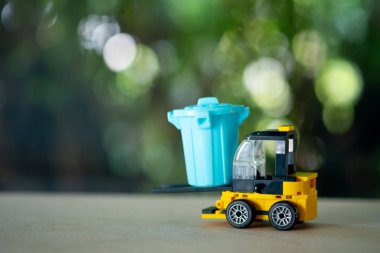 Sarı forklift oyuncağı mavi plastik çöp kutusunu yükle