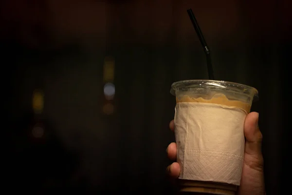 Hand holding iced latte with straw in plastic cup — Stock Photo, Image