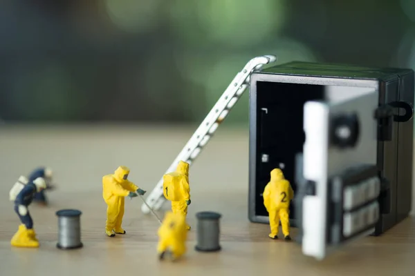 Equipo técnico en miniatura en trajes de materiales peligrosos están monitoreando contaminantes en caja de seguridad en la banca — Foto de Stock