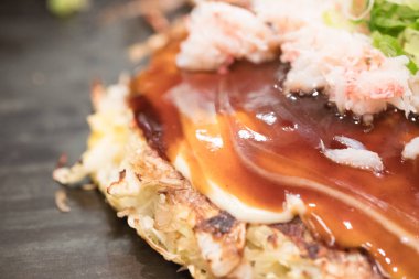Japon yerel yemekleri olan okonomiyaki ya da lahana etli erişte yumurtası ve soslu hiroşima pizzasına yakın çekim.