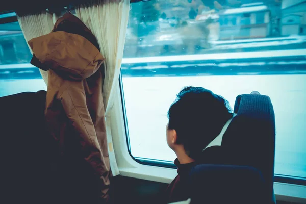 Homem asiático olhando através da janela com neve. Ele viaja em um trem em Hokkaido Japão. Conceito de viagem em Hokkaido durante a temporada de inverno — Fotografia de Stock