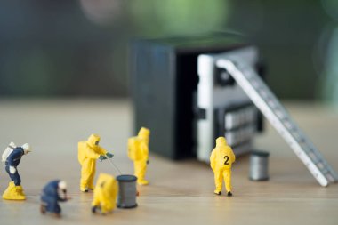 Tehlikeli madde giysileri içindeki minyatür teknik ekip, banka kasasındaki kirleticileri izliyorlar.