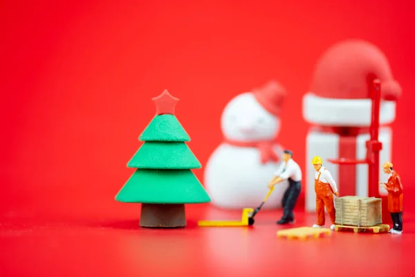 Personas en miniatura creando decoraciones navideñas sobre fondo rojo. Concepto creativo en Navidad — Foto de Stock