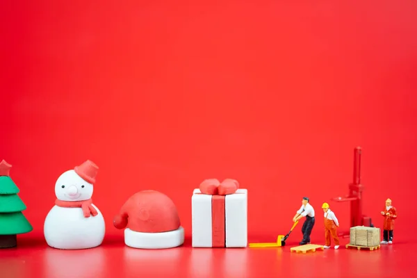 Miniatuur mensen maken kerstversieringen op rode achtergrond. Creatief concept in Kerstmis — Stockfoto
