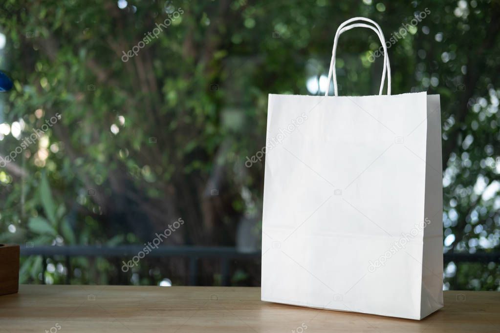White paper shopping bag standing on wood table