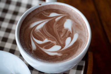 Beyaz bardakta sıcak çikolatalı latte.