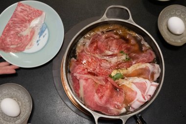 Japon sukiyaki yahnisi, sebze, biftek dilimi, Japonya 'nın Hokkaido şehrinde çiğ yumurta pişirme.