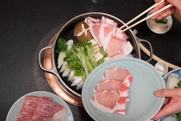 肉の牛のスライスと新鮮な野菜をすき焼きやしゃぶしゃぶの鍋に入れます。和食｜アジア料理 — ストック写真