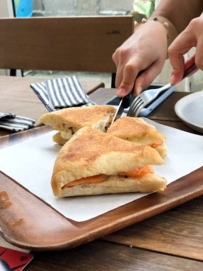 Üçgen dilim jambonlu ve peynirli sandviç yiyen kadın.