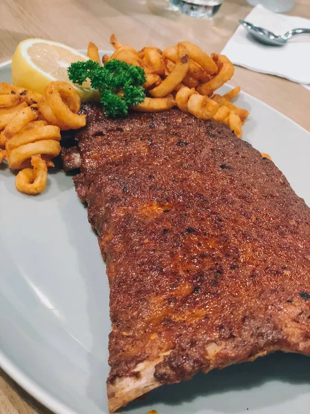 Costelas de porco grelhadas com molho picante de churrasco servido com batatas fritas . — Fotografia de Stock