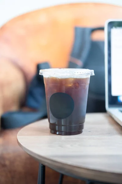 Черный кофе в пластиковой чашке с ноутбуком — стоковое фото