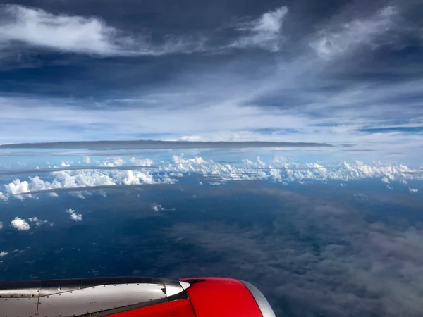 Красный двигатель, небо и облака через окно самолета — стоковое фото
