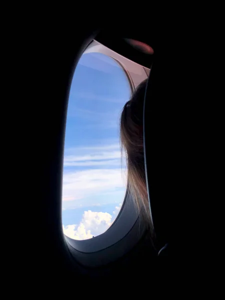 Задняя часть пассажира, смотрящего из окна самолета — стоковое фото