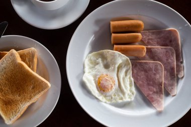 Ev yapımı kızarmış yumurta, tost, pastırma ve sıcak kahveyle servis edilen sosis. Kahvaltı ve içecek konsepti