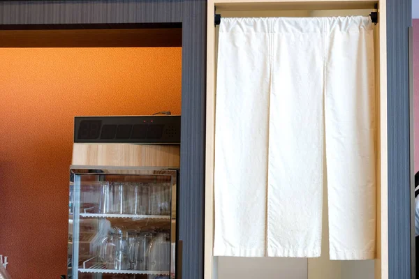 Empty glass in refrigerator cooler with banner hangs at the kitchen entrance of a restaurant in Japan