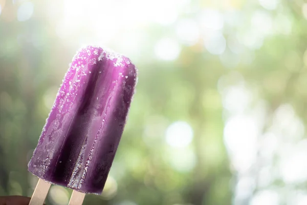 Grape flavored popsicle in hand